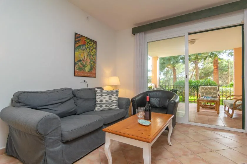 A living room with gray seating, a wooden coffee table, and sliding glass doors to a patio.
