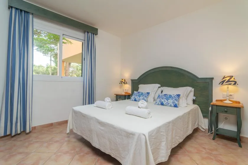 A bedroom with a double bed, blue curtains, and matching bedside tables.