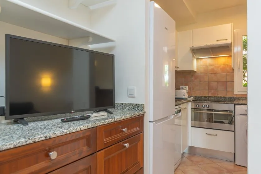 A kitchen with a television on the counter beside the cooking area.