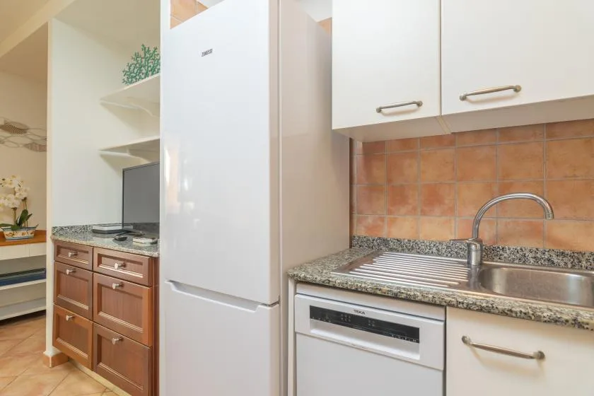 A kitchen with a refrigerator, countertop, sink, and built-in oven.