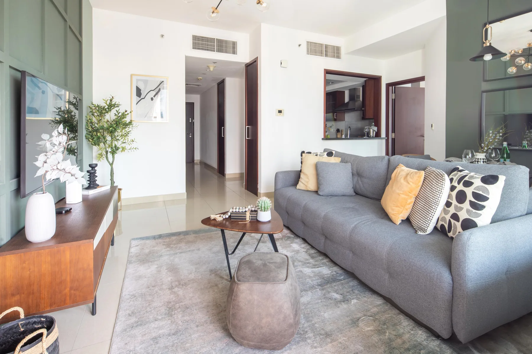 A bright living room with gray seating, a coffee table, and a television.