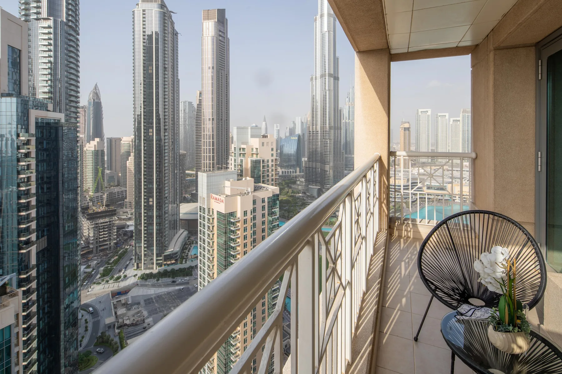 A balcony with seating overlooks a cluster of high-rise buildings.