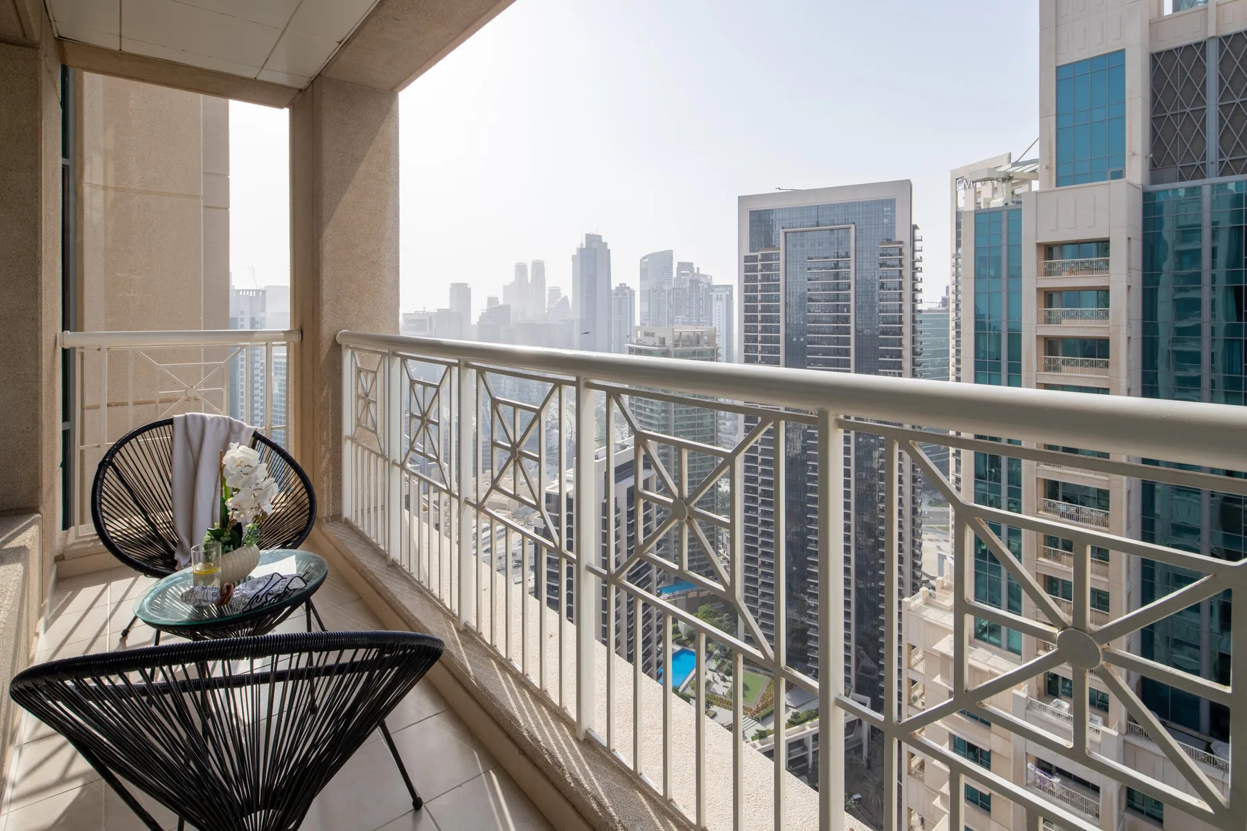 A balcony overlooks a city skyline, with seating beside the railing.