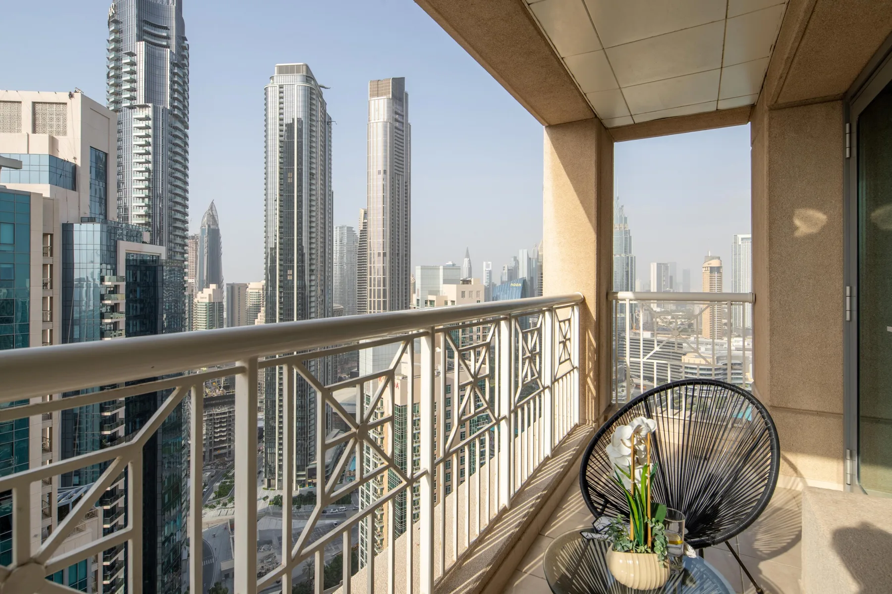 A high-rise balcony overlooks a cluster of modern city buildings.