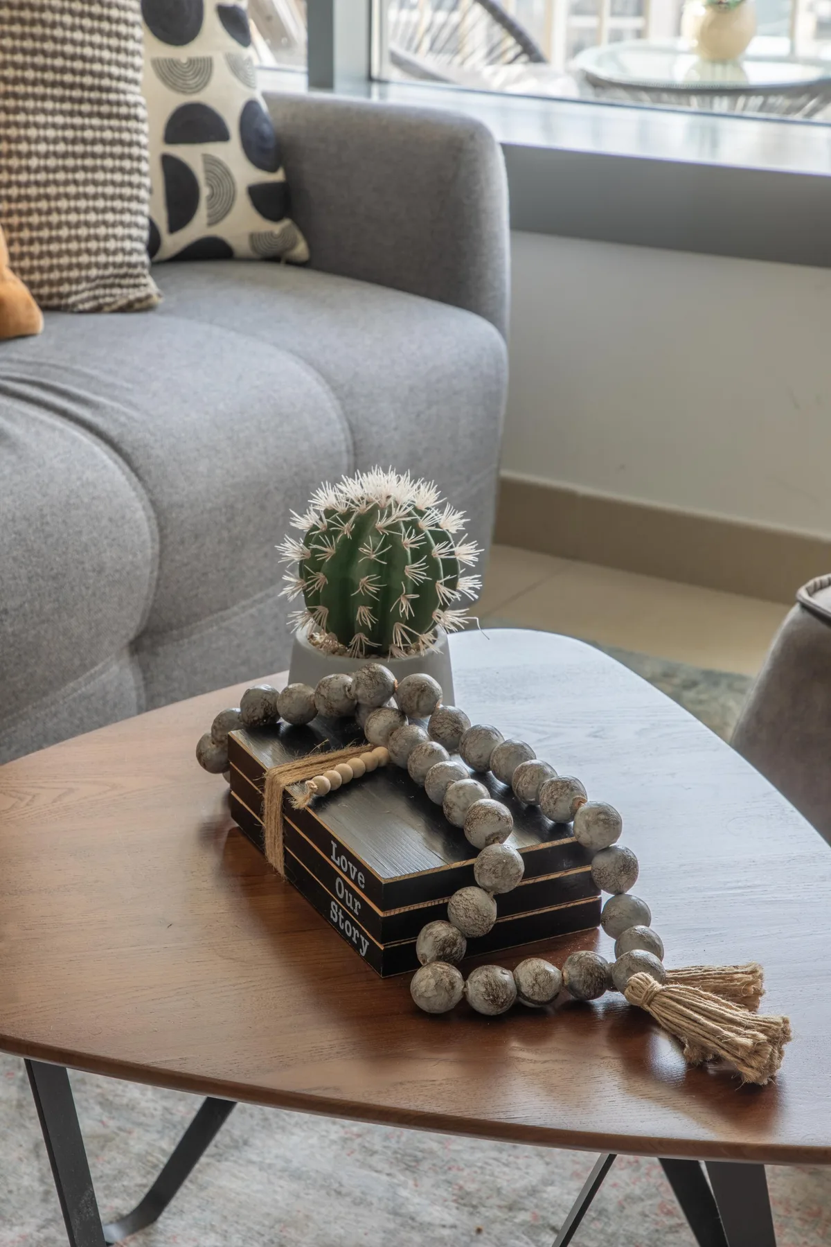 A living room seating area with a gray sofa and a cactus on the coffee table.