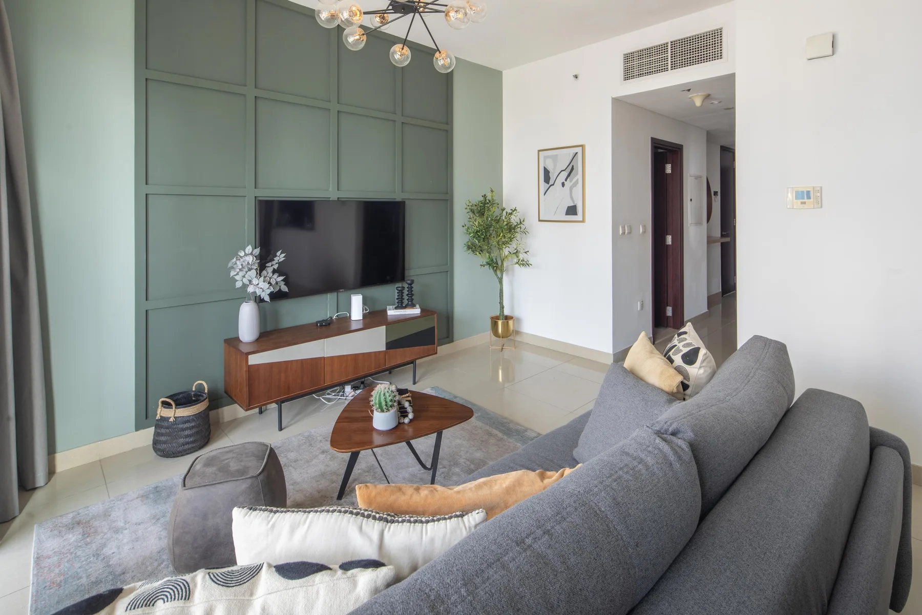 A modern living room with gray seating, a television, and a wooden coffee table.