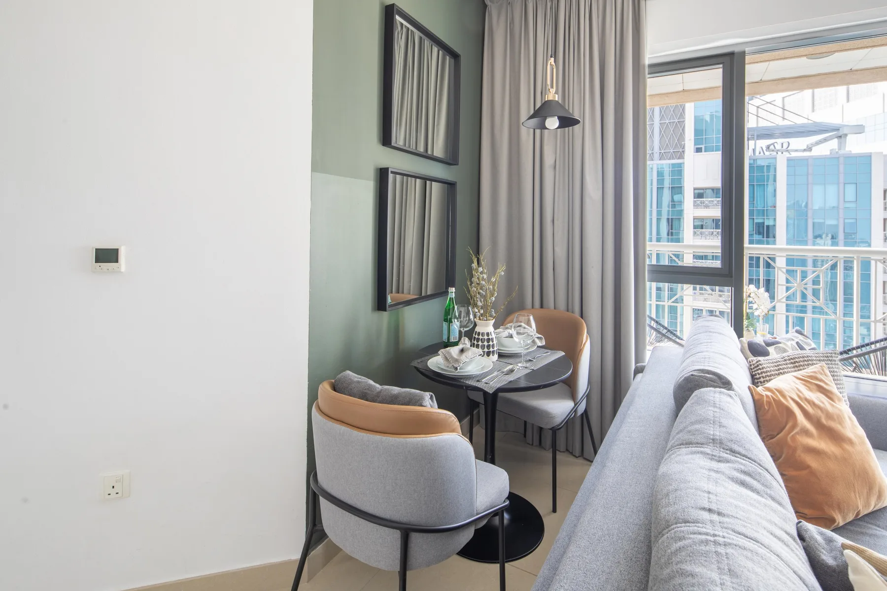 A bright living area with seating, a small dining table, and large windows.