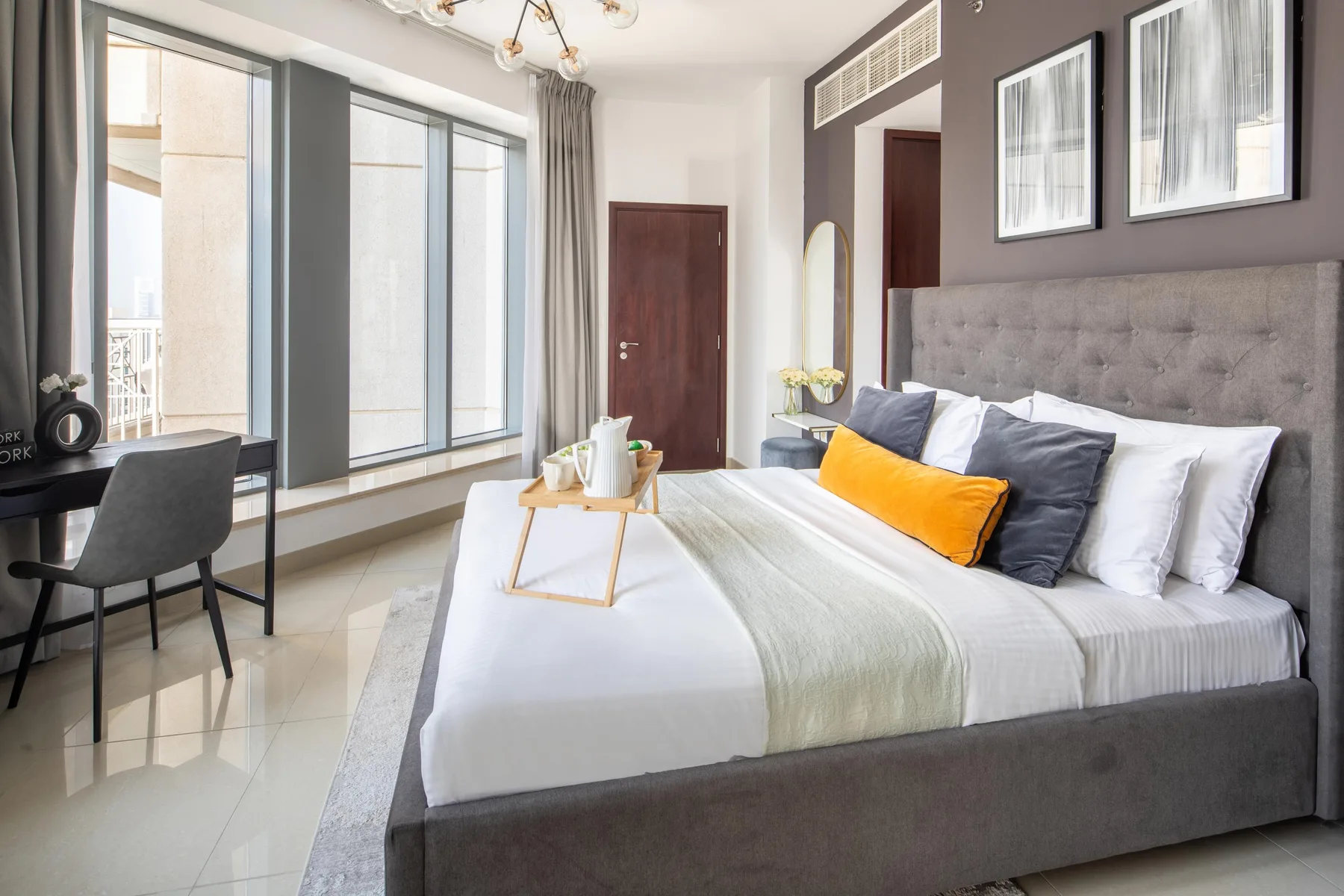 A bright bedroom with a neatly made bed and large windows.
