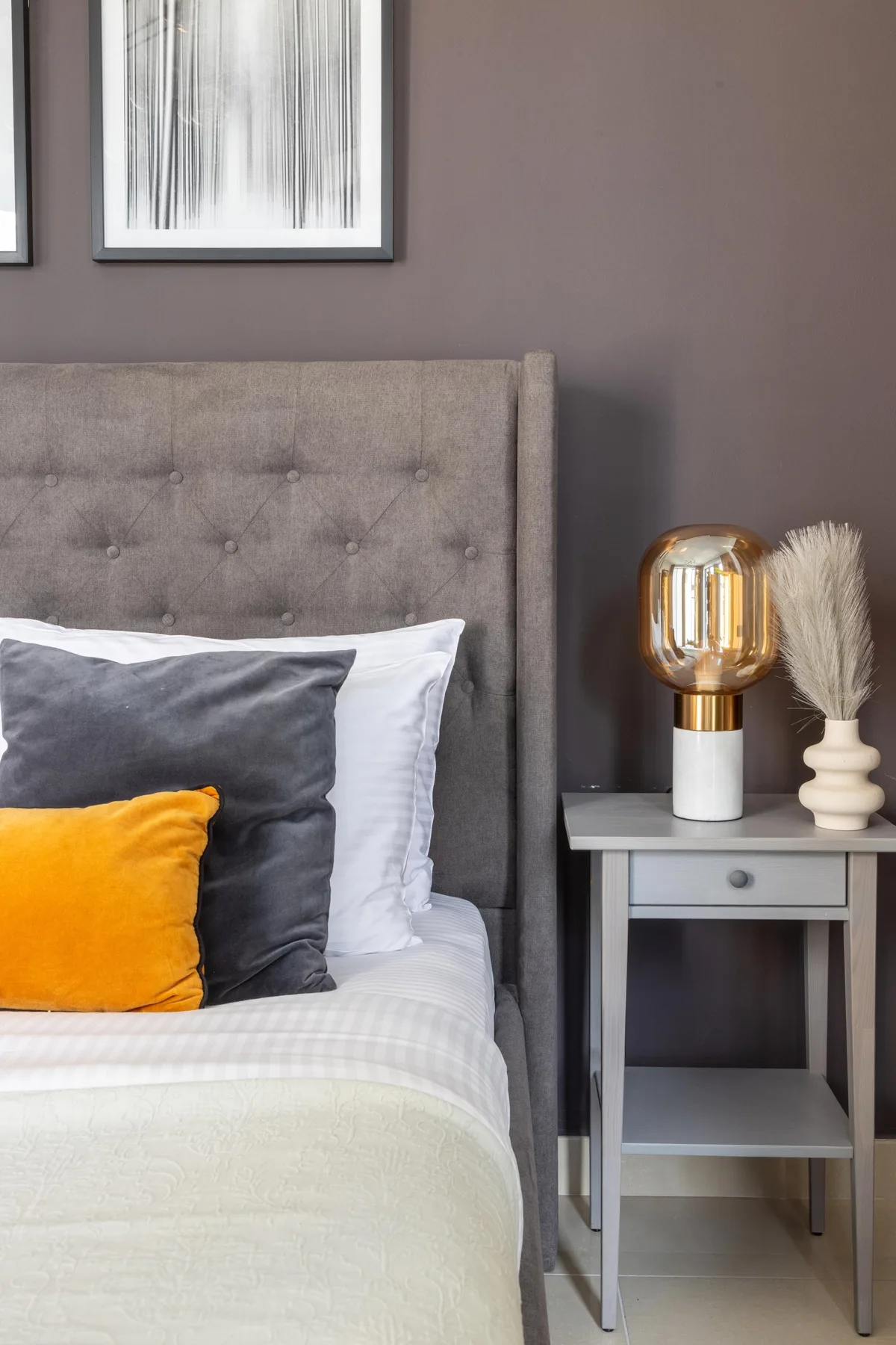 A bedroom with a neatly made bed and a small bedside table.