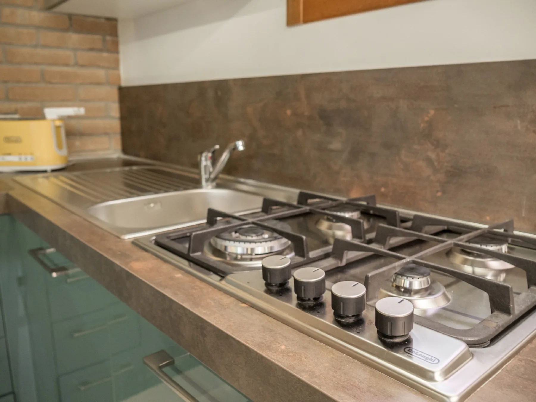 Una encimera de cocina con fregadero, escurridor y cocina de gas.