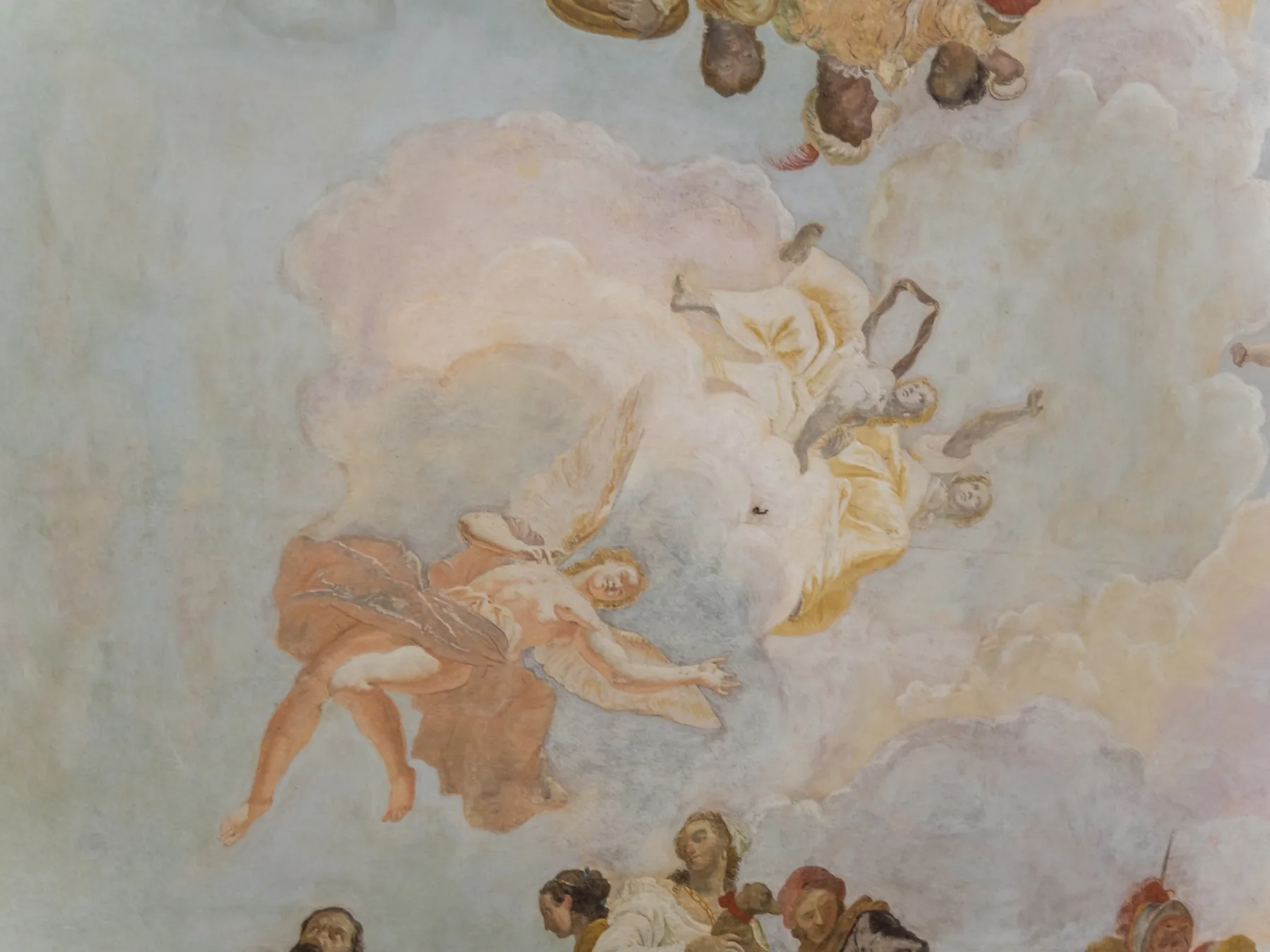 Un mural pintado en el techo muestra figuras flotando entre nubes.