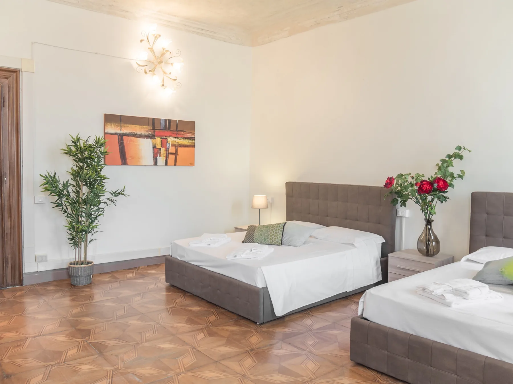 Un dormitorio con dos camas, mesitas de noche y una planta en maceta.