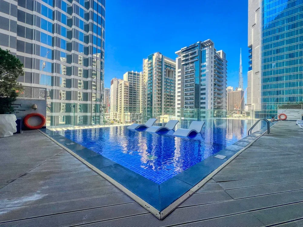 Una piscina al aire libre se encuentra entre edificios altos.