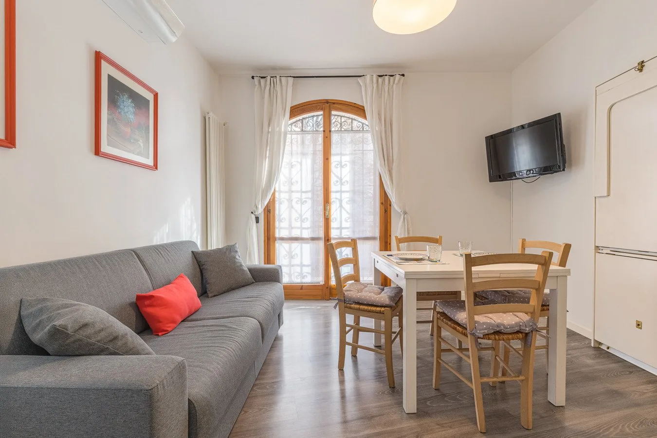 Una sala de estar y comedor con asientos, una mesa y una puerta acristalada.