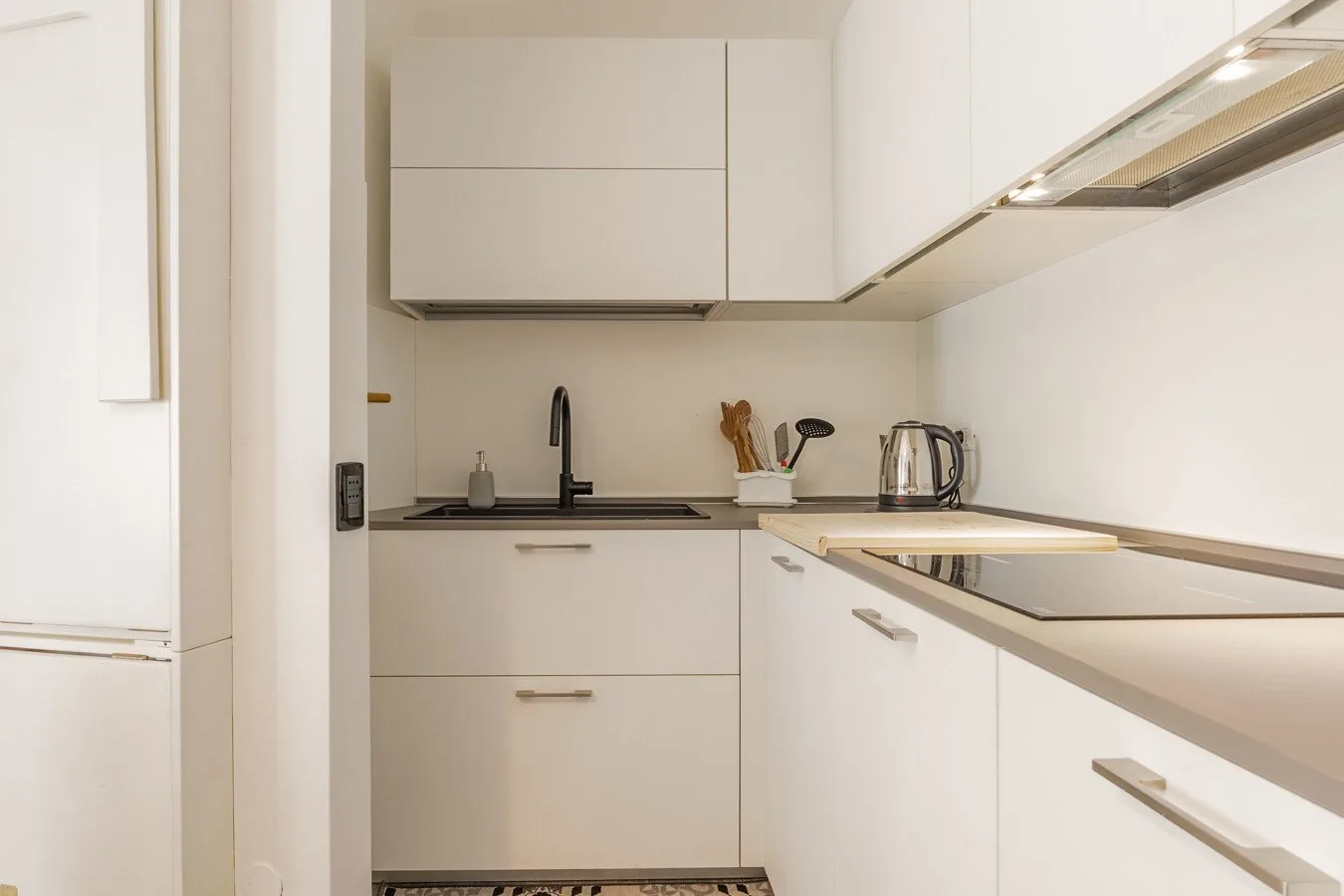 Una cocina compacta con gabinetes blancos y una encimera oscura.
