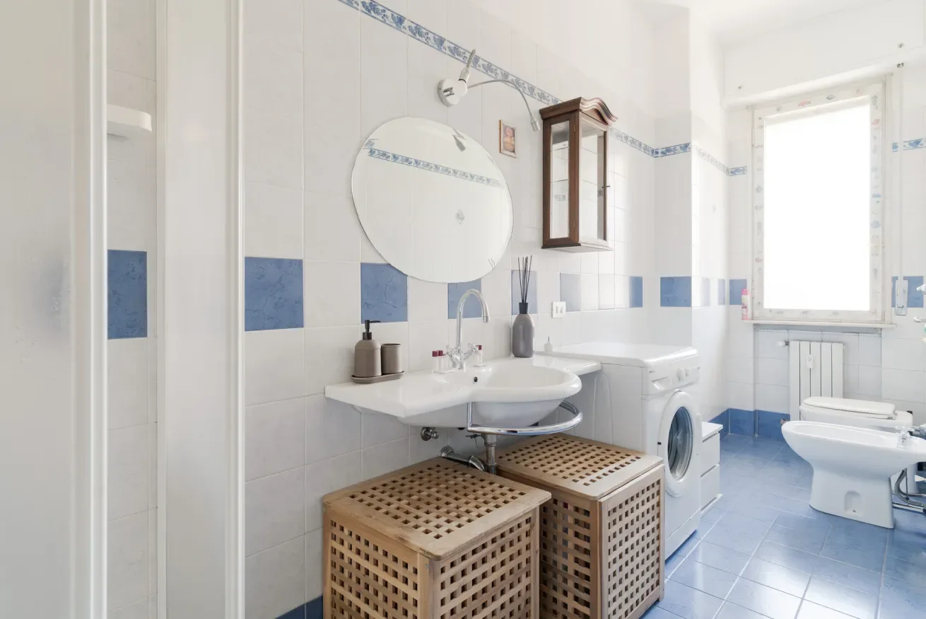 A tiled bathroom with a sink, washing machine, and toilet.
