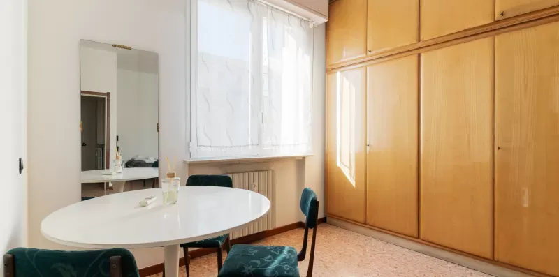 A bright dining area with a white table beside a large window.