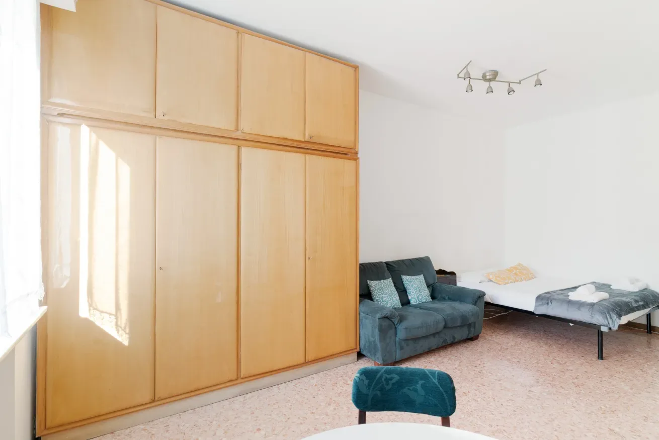 A bedroom with a bed, seating, and a large wooden wardrobe.