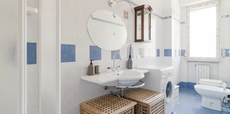 A tiled bathroom with a sink, washing machine, and toilet.