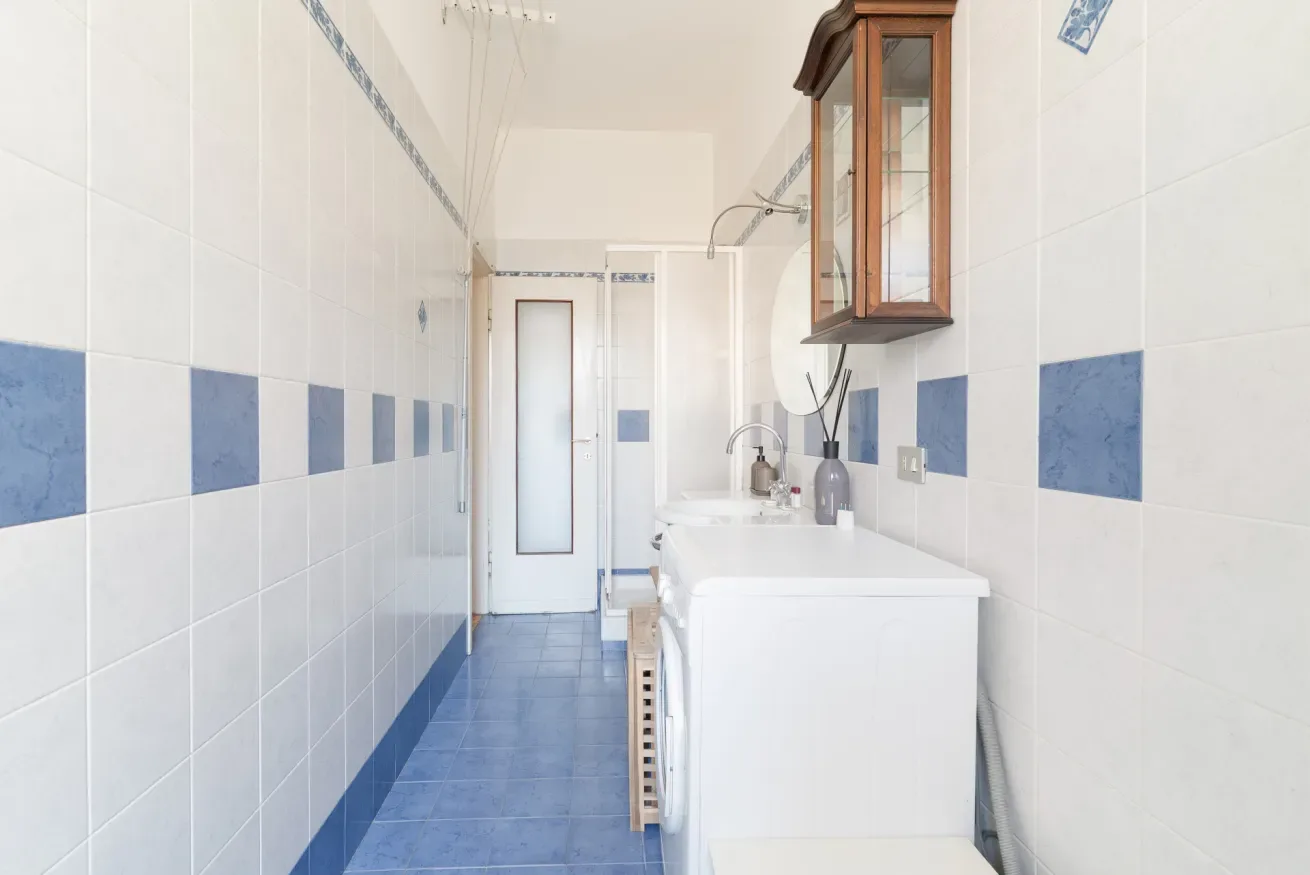 A tiled bathroom with a sink and blue floor tiles.