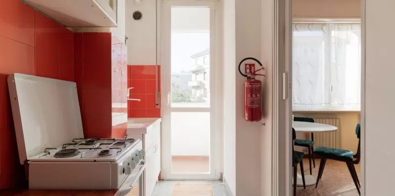 A kitchen with a stovetop beside a bright doorway and dining table.