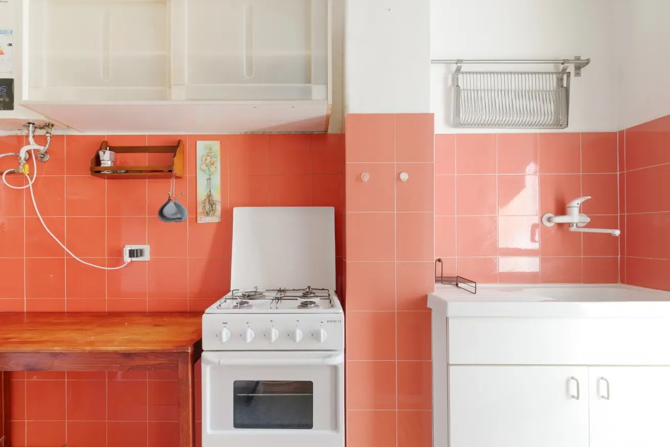 A kitchen with a stove beside a sink set into the counter.