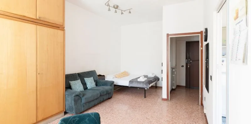 A living room with seating beside a bed and an open doorway.