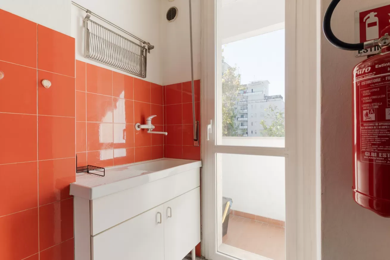 A bathroom with an orange-tiled sink beside a bright window.