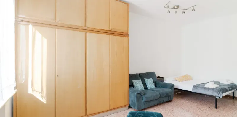 A bedroom with a bed, a seating area, and large wooden wardrobes.