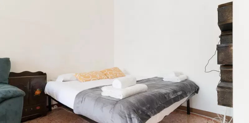 A bedroom with a bed dressed in gray bedding and folded towels.