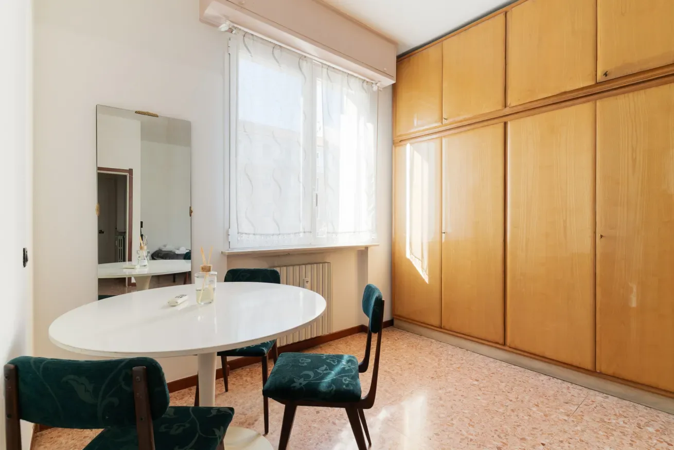 A bedroom with a round table and built-in wooden wardrobes.