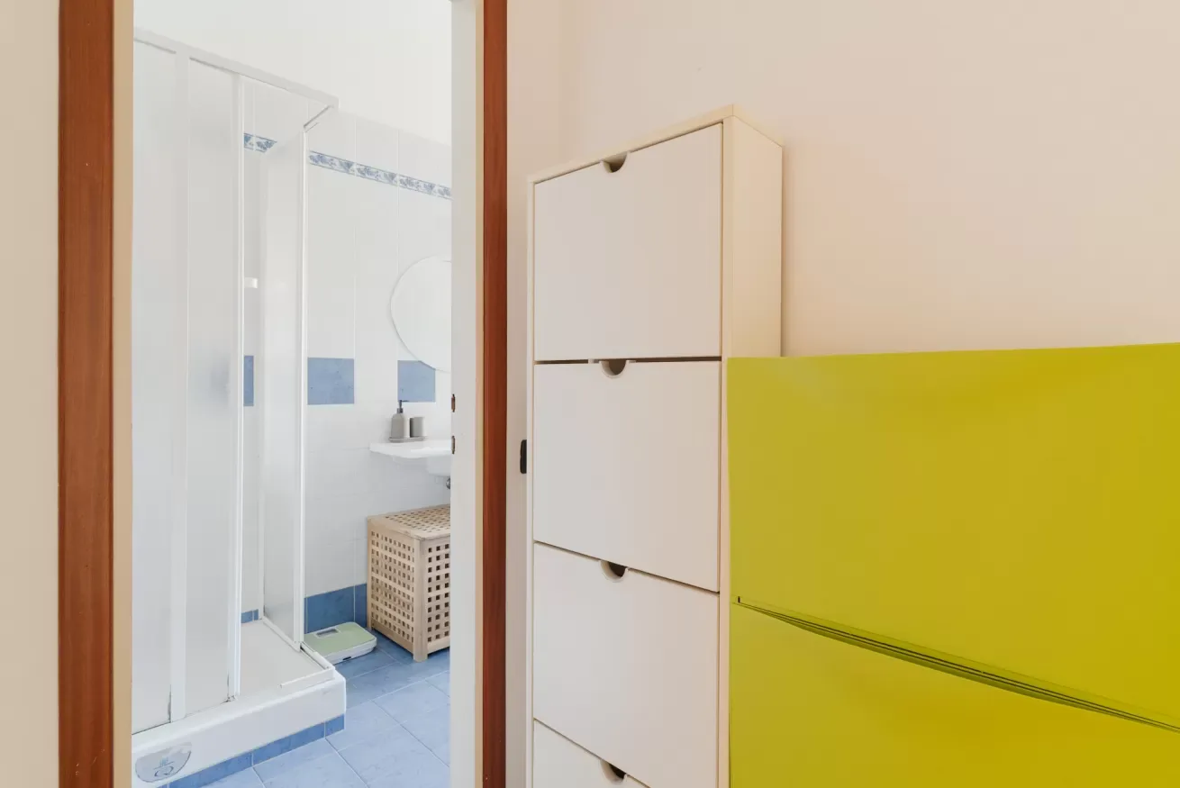 A bathroom with a shower and a white storage cabinet.