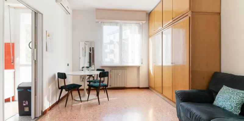 A bright room with seating, a window, and built-in cabinets.