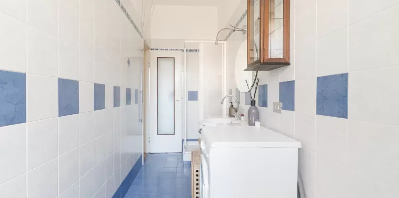 A tiled bathroom with a sink and a glass shower enclosure.