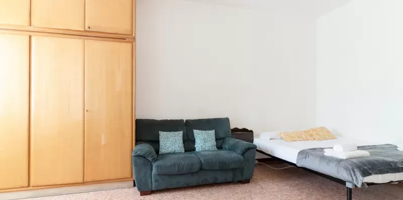 A bedroom with a dark seating area beside a bed.