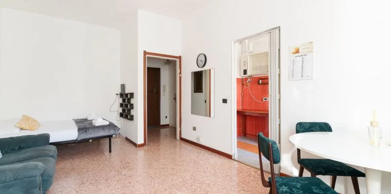 A bright dining area with a white table and teal chairs beside a doorway.