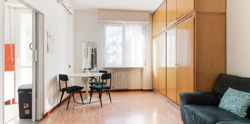 A bright room with a table and chairs beside a large wooden wardrobe.