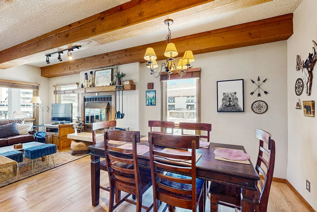 Comedor con mesa de madera y asientos bajo vigas expuestas.