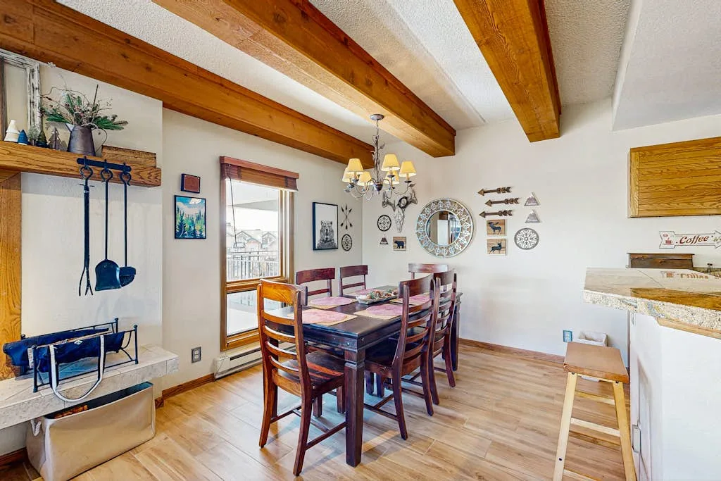 Un comedor con una mesa de madera bajo vigas expuestas.
