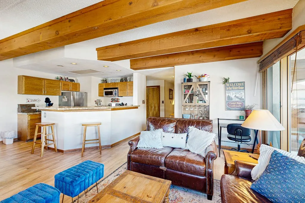 A living room with leather seating, a coffee table, and an open kitchen.