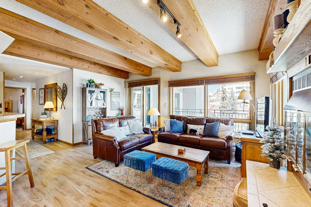 A living room with seating, a coffee table, and exposed wooden ceiling beams.