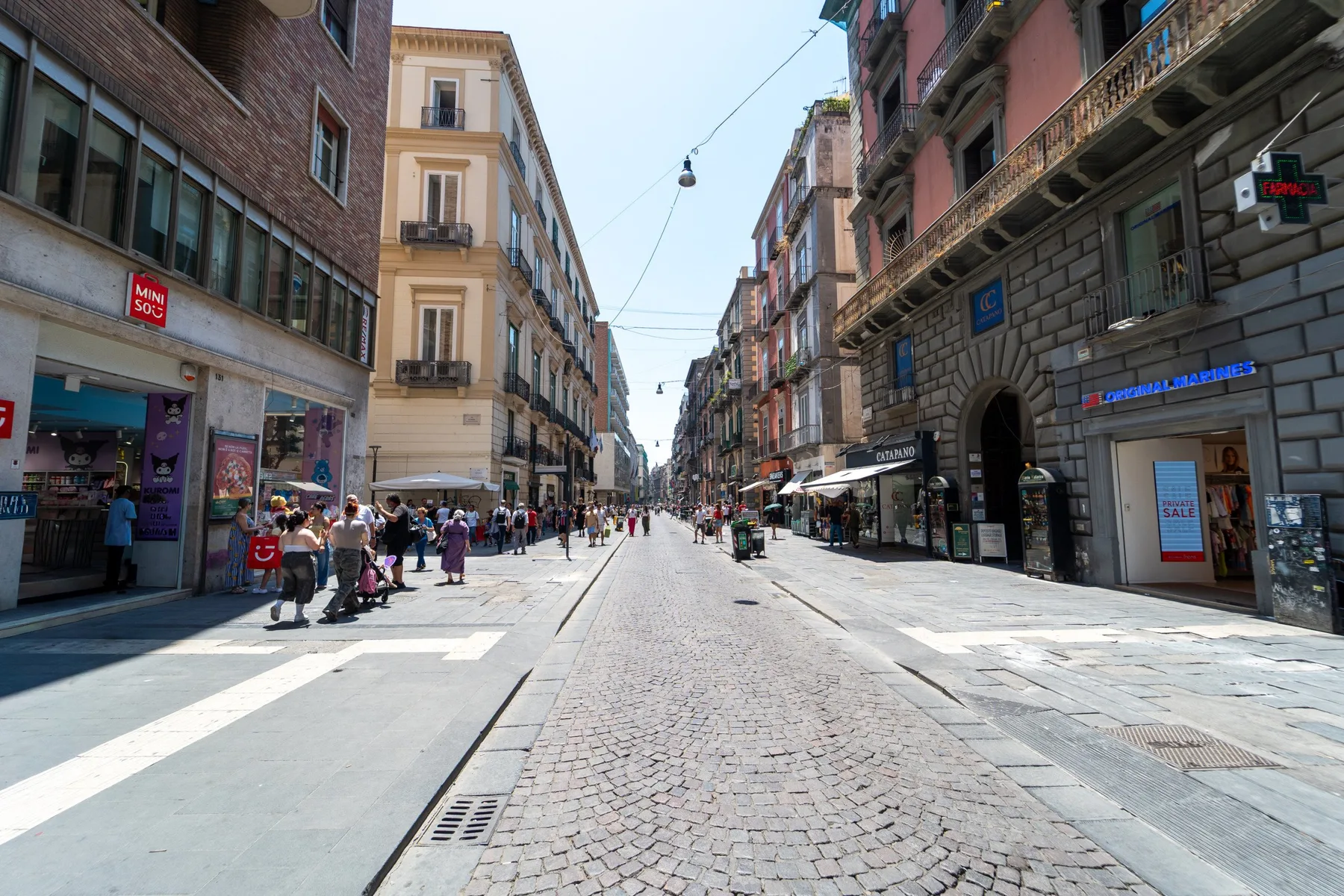 Una calle peatonal pasa entre edificios de varias plantas, con personas caminando por la calzada.