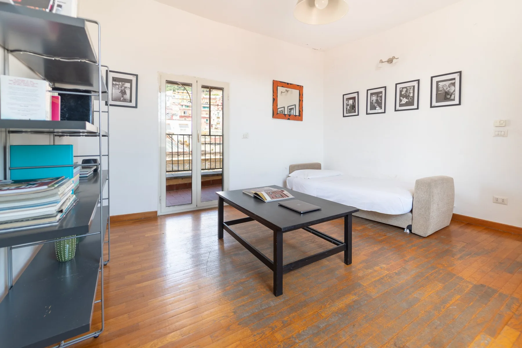 Una habitación luminosa con una cama, una mesa de centro oscura y cuadros en la pared.