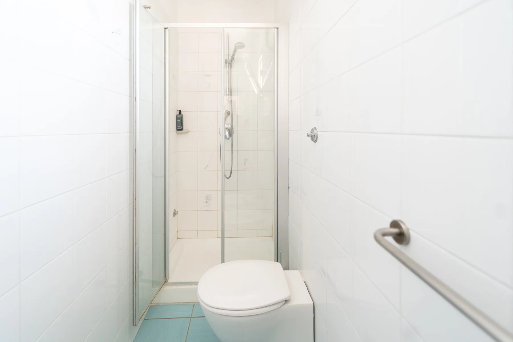 Un baño alicatado con ducha e inodoro.