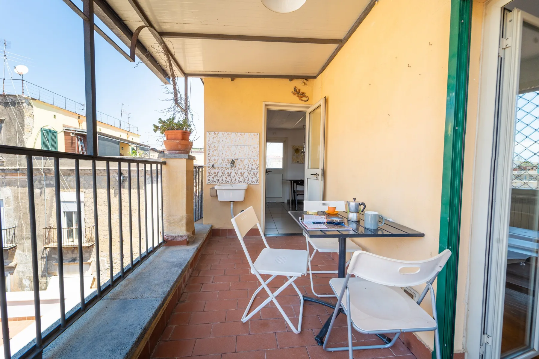 Una terraza cubierta con una mesa y sillas plegables junto a una puerta abierta.