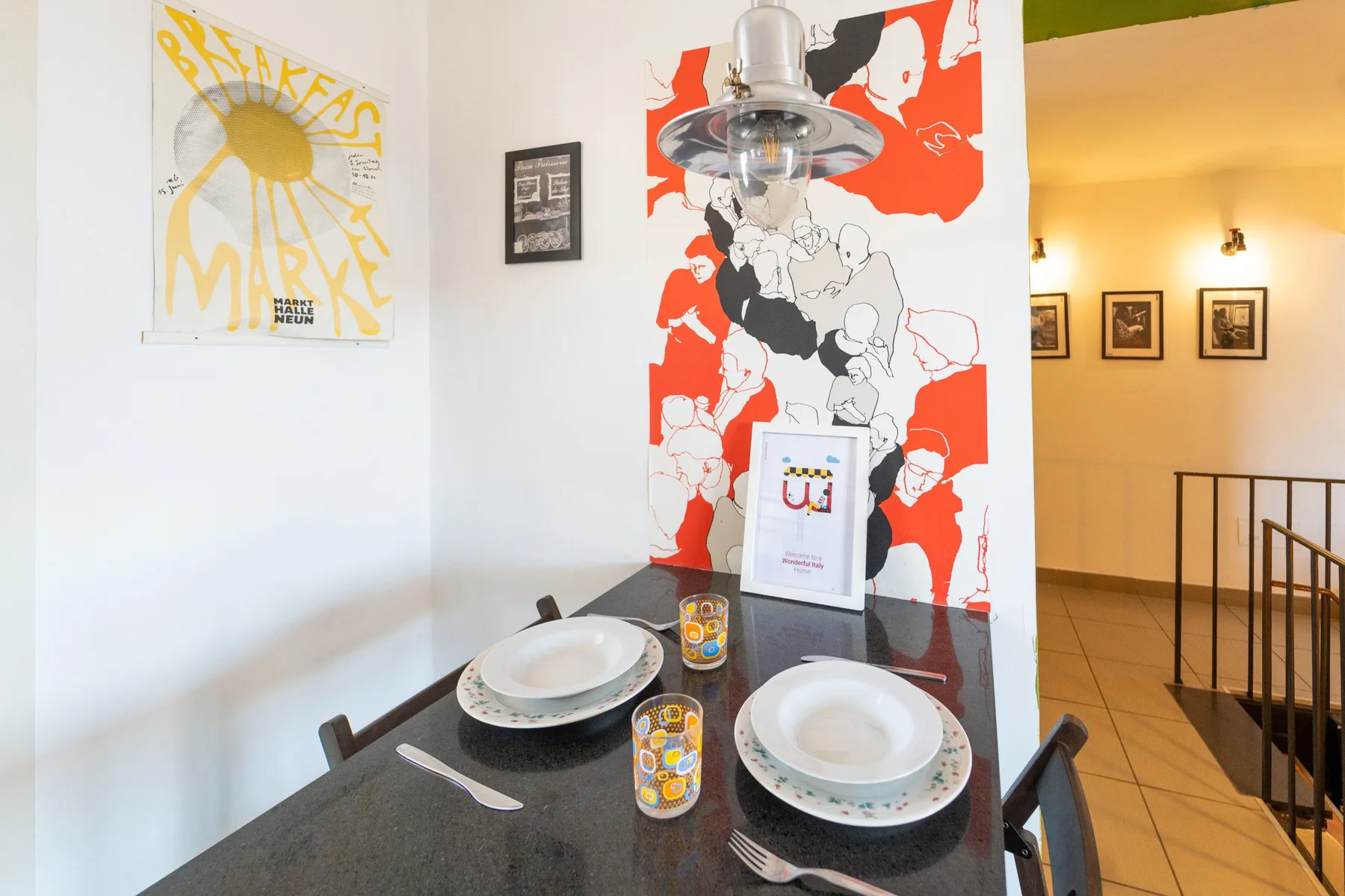 Una mesa de comedor con vajilla está junto a un mural colorido.
