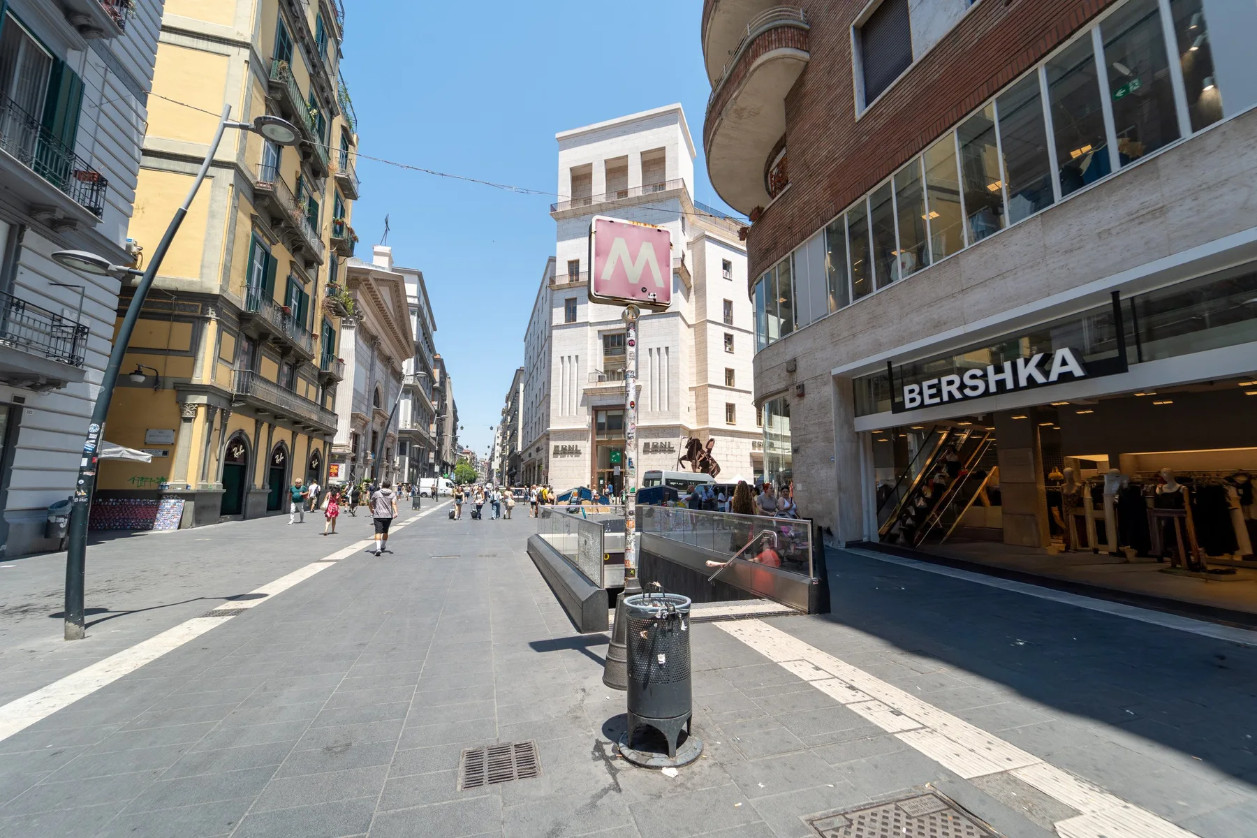 Una calle comercial peatonal bordeada de tiendas y edificios altos.