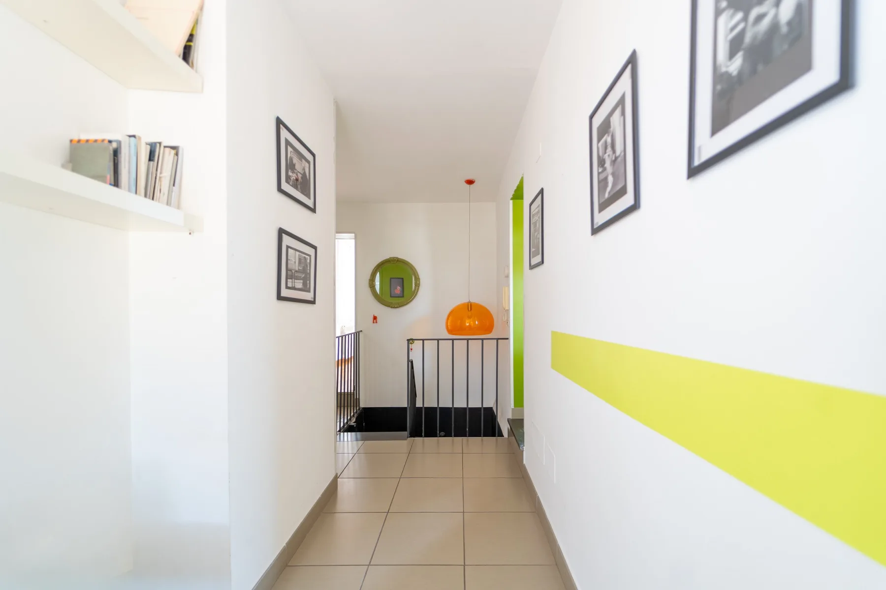 Un pasillo luminoso con cuadros enmarcados y una franja verde lima en la pared.