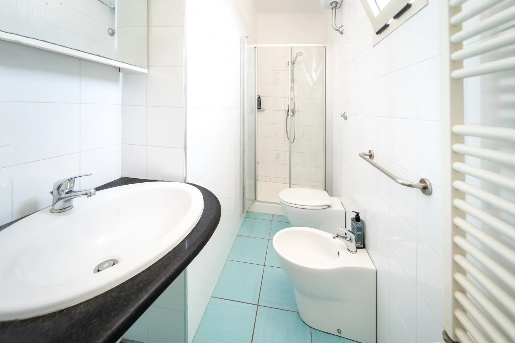 Un baño luminoso con azulejos, lavabo, inodoro y ducha.