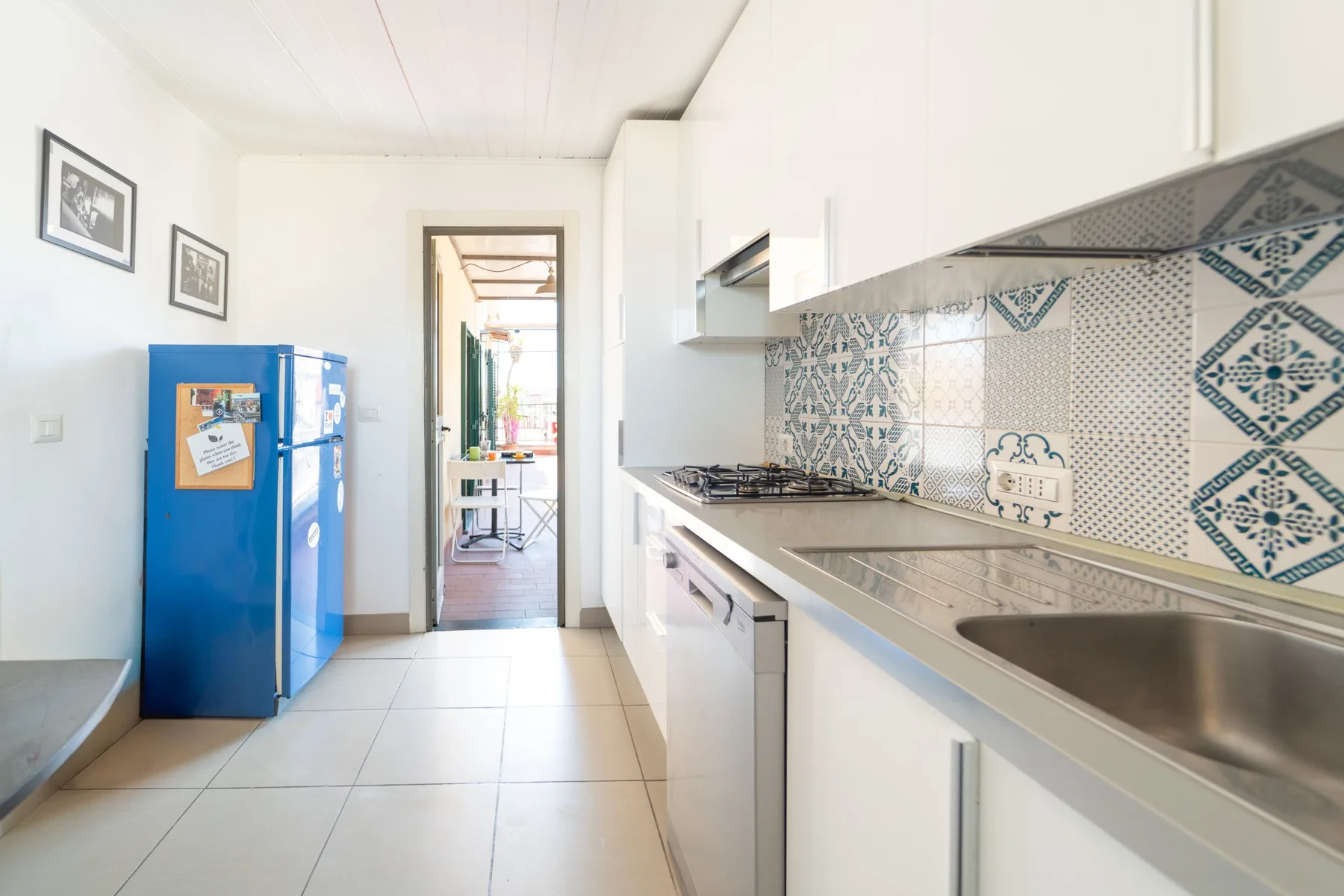 Una cocina luminosa con una encimera larga, fregadero y azulejos decorados.